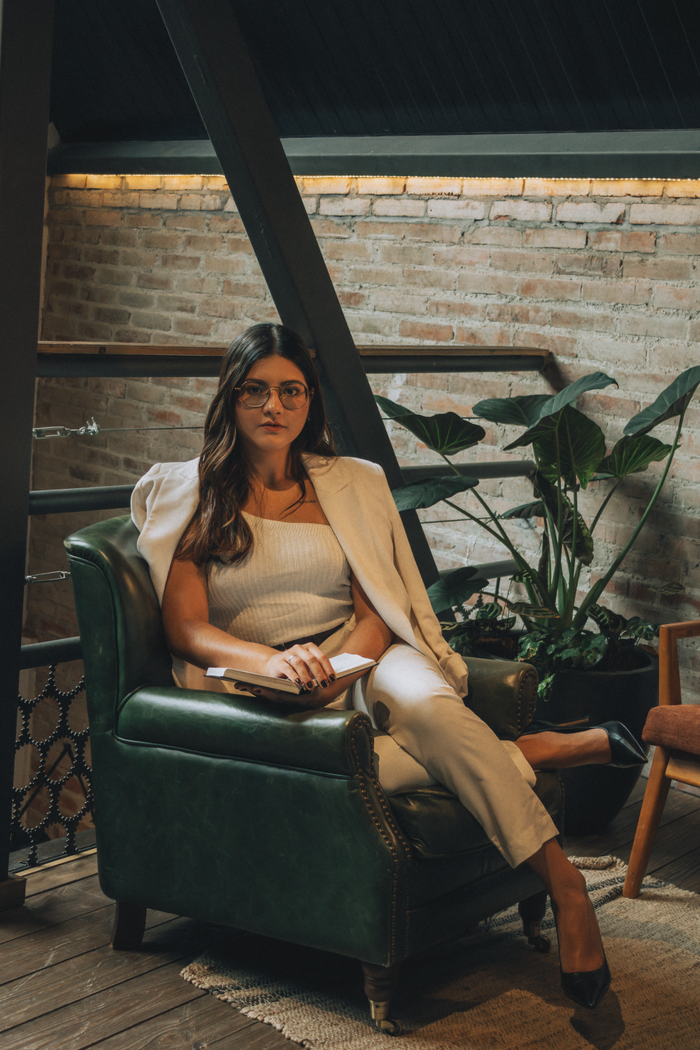 Professional woman in stylish outfit sitting in a modern interior, exuding confidence and sophistication.